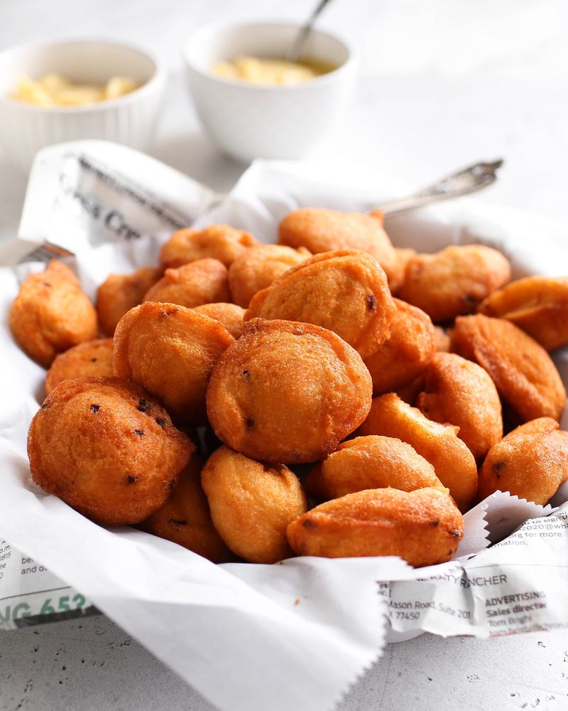 A basket of golden fried akara beans balls lined with newspaper