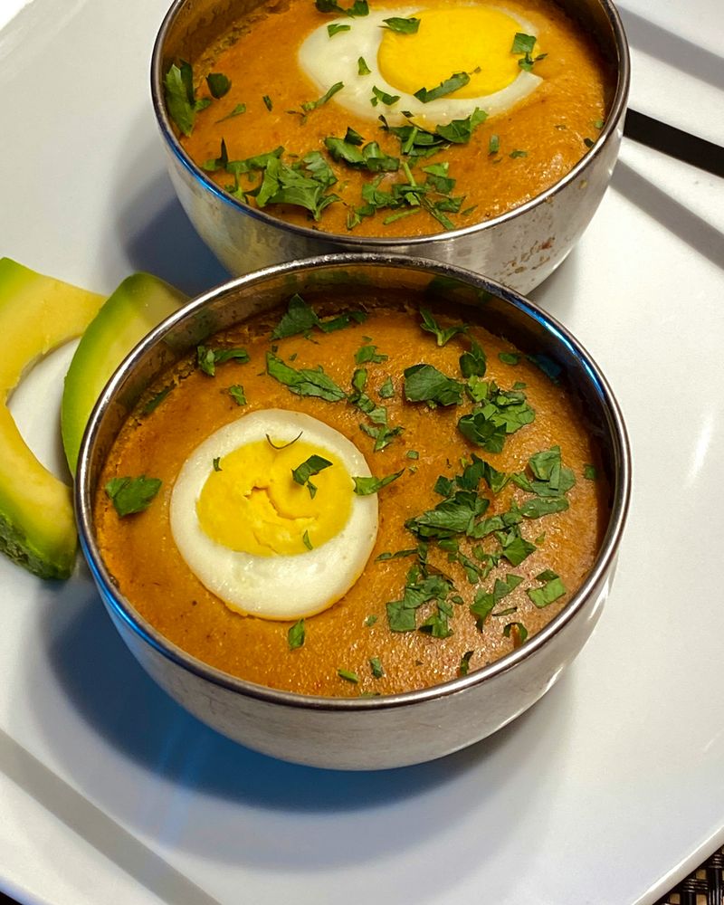 Two bowls of steamed bean pudding topped with boiled egg and herbs